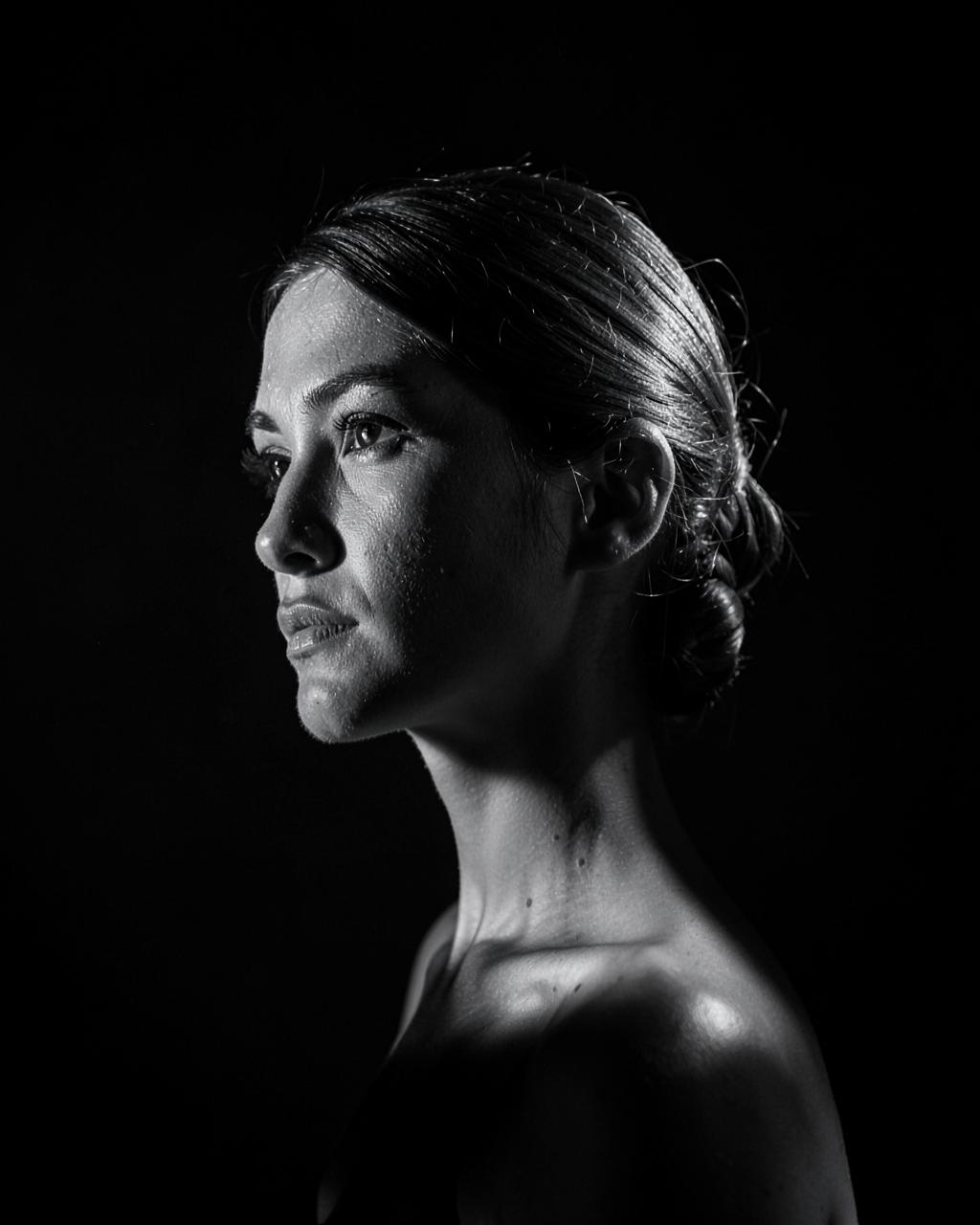 Dramatic studio portrait of a woman in profile lit by a single hard light